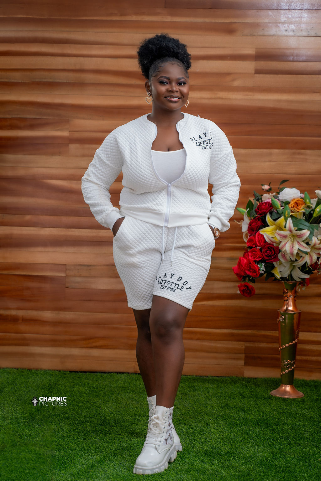 A woman in a white outfit standing beside a floral arrangement - Chap Nic Pictures
