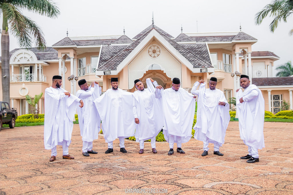 A wedding party dressed in white outside a grand entrance